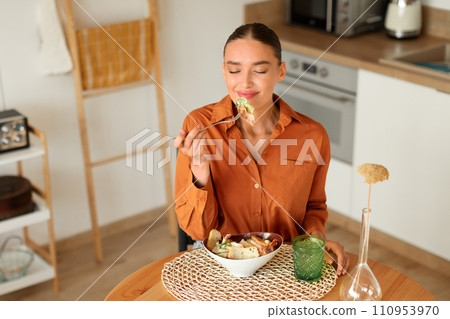 Woman tasting salad in a cozy kitchen setting 110953970