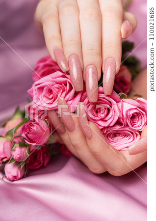 Female hands with pink nail design  hold pink roses 110021686