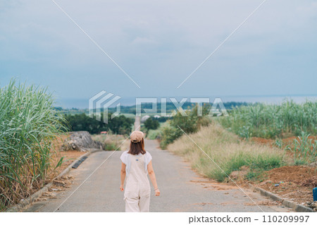 一個女人走過通往大海的甘蔗田 110209997