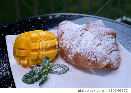 Morning breakfast with croissant and orange juice in glass, yellow roses on vintage silver tray. 110249572