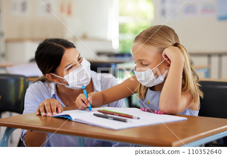 Education, covid and learning with face mask on girl doing school work in classroom, teacher helping student while writing in class. Elementary child wearing protection to stop the spread of a virus 110352640