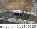 Red car covered in snow is parked between two fences. 111549185