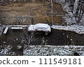 Car covered in snow is parked on street next to tree and fence. 111549181