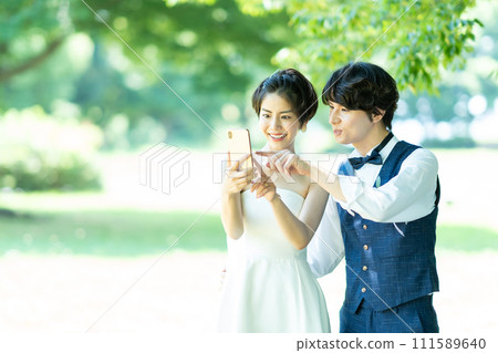 Bride and groom taking photos with smartphone 111589640