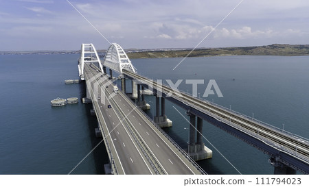 Top view of suspension bridge on water. Shot. Cars are driving on white suspension bridge over blue water. Beautiful seascape with Crimean suspension bridge 111794023