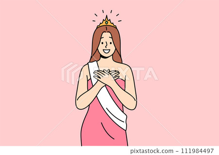 Woman won beauty contest smiles with hands on chest, dressed in dress with winner ribbon and crown 111984497