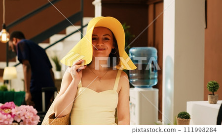 Tourist at exotic resort reception asking about booking reservation in lobby entrance. Woman guest client preparing for check in tropical seaside hotel, international summertime trip. 111998284