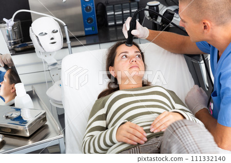 Woman getting facial electroporation procedure in aesthetic medicine office 111332140