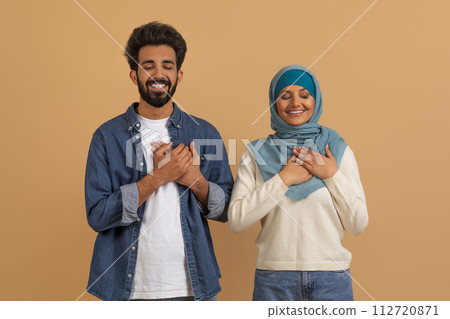 Thankful Muslim Couple Keeping Hands On Chest, Expressing Gratitude Together 112720871