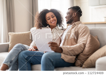 Happy black millennial couple managing paperwork together at home 112724489