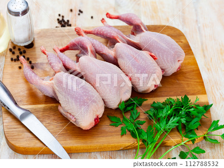 Raw gutted partridges on wooden table with seasonings and greens 112788532