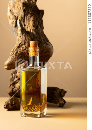 Bottle of spicy olive oil and olive tree snag on a beige background. 112887220