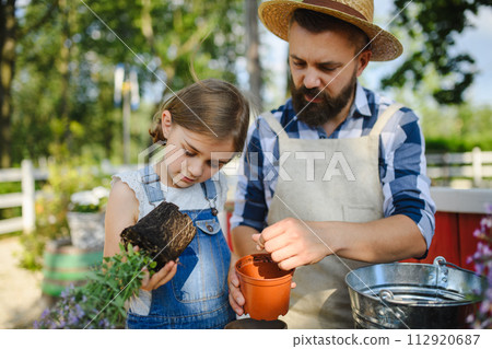 Father and young daughter planting lavender plant in pot at family farm. Concept of multigenerational farming. 112920687