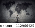 Person stands in front of a concrete wall looking at the world map. Travel limitations concept 112966425