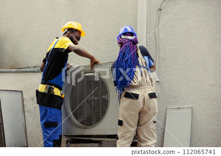 African american expert repairmen pulling apart air conditioner panel with industry techniques and equipment to mend air filters, electrical system issues and frozen evaporator coils 112065741