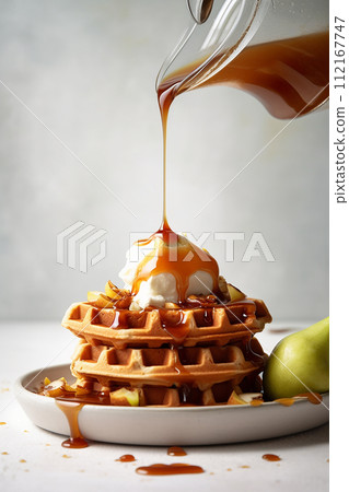 Vanilla ice cream on waffles drizzled with caramel sauce and nuts. 112167747