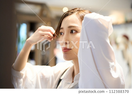 一個女人照鏡子並穿衣服 112388370