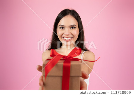 Happy woman offering a gift with red bow 113718909