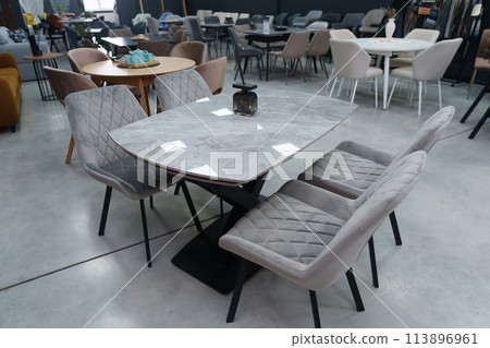 Gray wooden table complete with gray wooden chairs with soft fabric upholstery. Black glass jar with incense sticks on the table 113896961