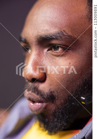 African american streamer competing in intense online multiplayer videogame, streaming live at home, close up shot. Man playing on gaming PC, using headphones to discuss with viewers 113009891