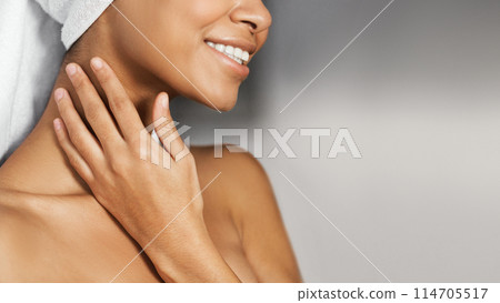 Smiling afro-american girl with naked shoulders and towel on head touching her neck, copy space. Daily spa concept 114705517