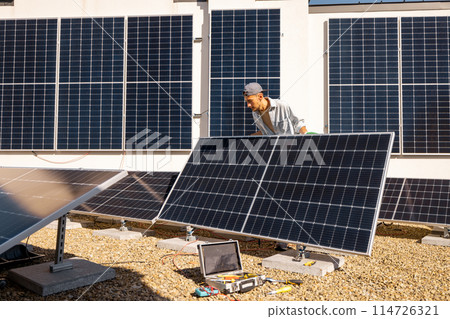 Man installing solar panels on the roof of his house 114726321