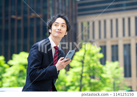 A businessman using a smartphone with wireless earphones 114125150