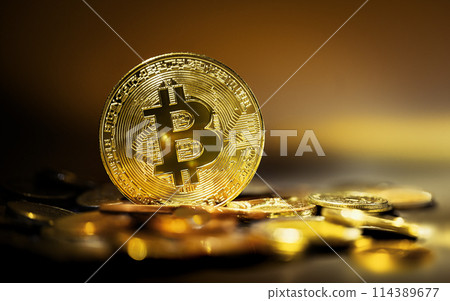 Gold bitcoin atop a pile of gold coins, closeup view 114389677