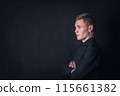 Serious contemplative young man side view portrait, looks pensive against a dark wall background. Male student reflects as have questions 115661382