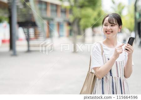 A young woman operating a smartphone 115664596