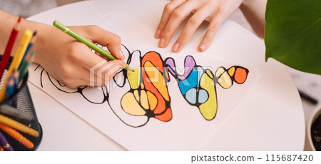 Lady paints over a drawing on a white sheet with colored pencils 115687420