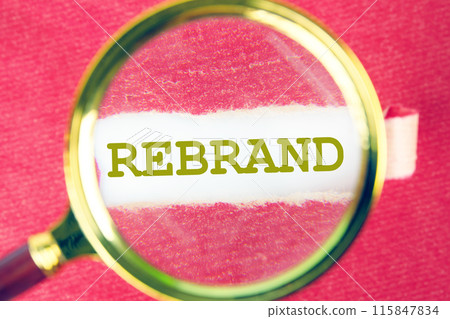 Rebrand and Business concept. Copy space. Rebrand symbol through a magnifying glass under a torn piece of red paper 115847834