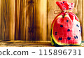 Watermelon bag sitting on top of wooden table next to wooden fence. 115896731