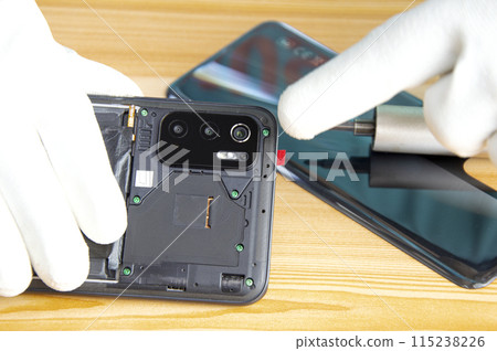 Image of a technician screwing the back of a mobile phone 115238226