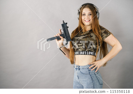 Woman wearing headphones holding gun 115350118