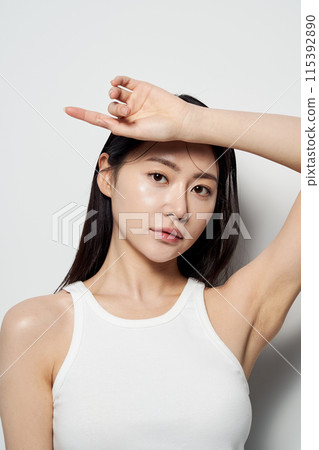 an Asian woman with one hand on her forehead against a white background 115392890