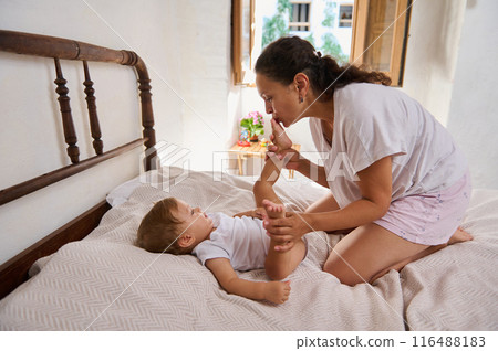 Mother lovingly plays with her baby in a cozy bedroom on a sunny day 116488183