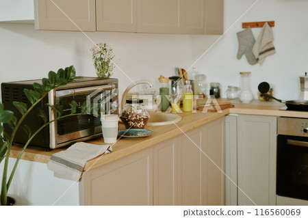 Medium close up of wooden kitchen counter with kitchenware and electronic device on top in comfort cook zone 116560069