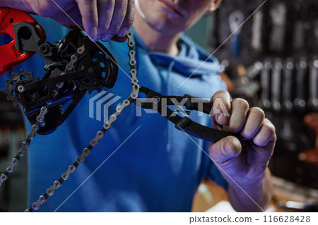 Professional male mechanic engaged in bicycle chain removal 116628428