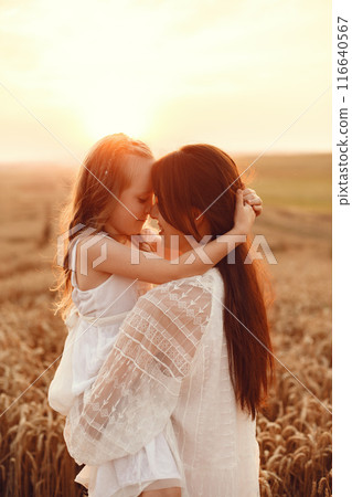 Family in a summer field. Sensual photo. Cute little girl. Woman in a white dress. 116640567