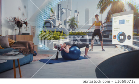 Sportswoman in AR headset exercises with fitball. VR screen shows virtual trainer and fitness app 116690712