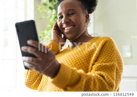 Happy senior african american woman using smartphone at home 116812549