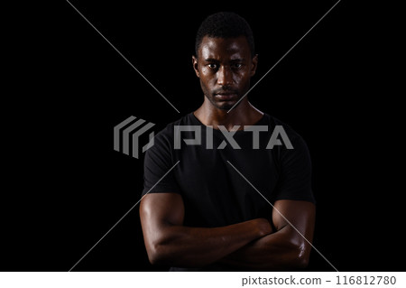 African American man stands confidently against a dark background on black background 116812780