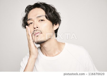 A man holding his hand on his cheek against a white background 116870020