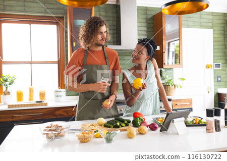 A diverse couple is preparing meal together in a modern kitchen 116130722