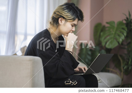 A man in his twenties working on a laptop 117468477