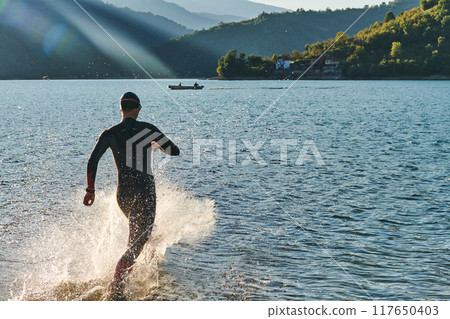 Triathlon athlete starting swimming training on lake 117650403