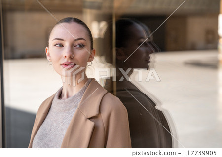 Young beautiful woman wearing coat walking in the city centre of Prague, Europe 117739905