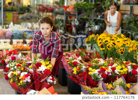 Adult female seller holding bouquet of flowers 117764176