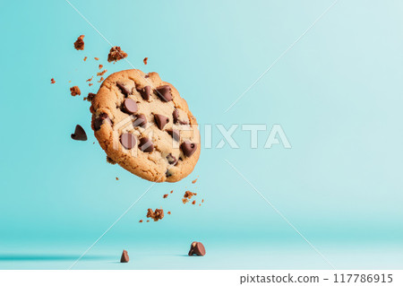 A delicious chocolate chip cookie flying through the air, breaking apart with crumbs, showcasing its tempting texture. 117786915